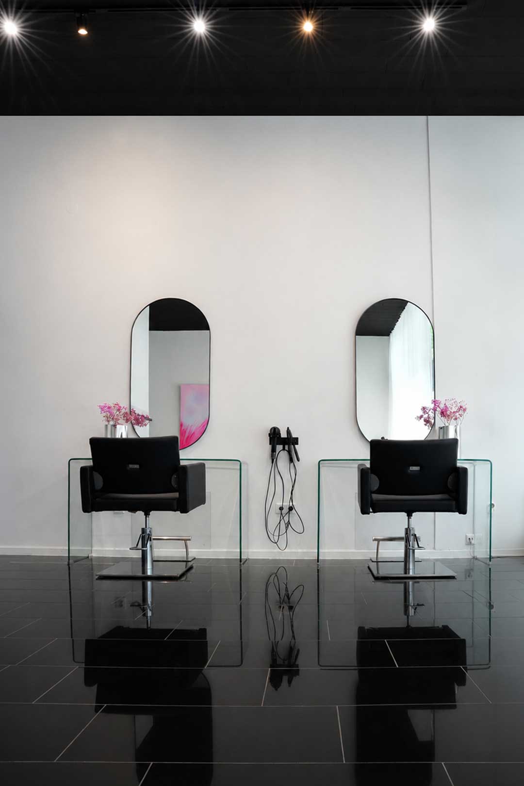 Zwei Friseurstühle vor ovalen Wandspiegeln
