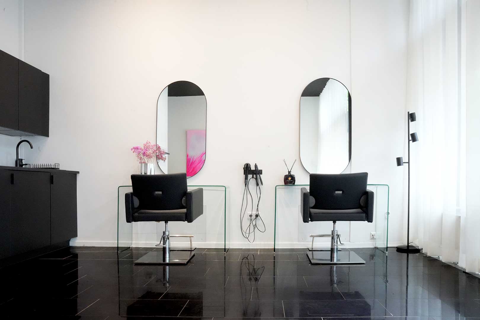 Salonraum mit zwei Friseurplätzen und schwarzer Schrankzeile